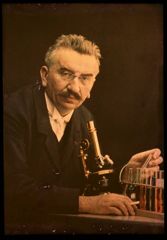 Louis Lumiere avec un microscope et des tubes à essais.